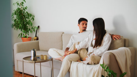 Smiling couple embracing sofa closeup. Cute woman stroking man face relaxing beige couch. Happy family bonding talking at warm weekend. Positive lovers having good time in living room together at homeの写真素材