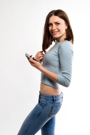 pretty girl teenager in jeans mobile phone on a white backgroundの写真素材