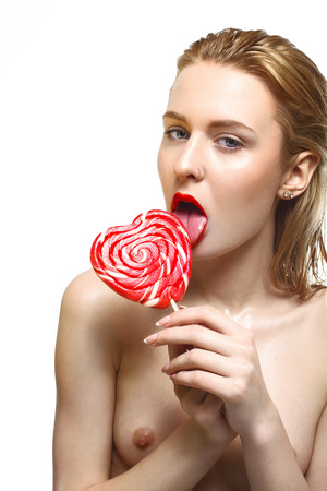 young sexy nude blonde posing topless for beauty with red sweet candyの写真素材