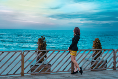 stylish and fashionable young brunette girl in yellow spring color dress posing on the beach against the seaの写真素材