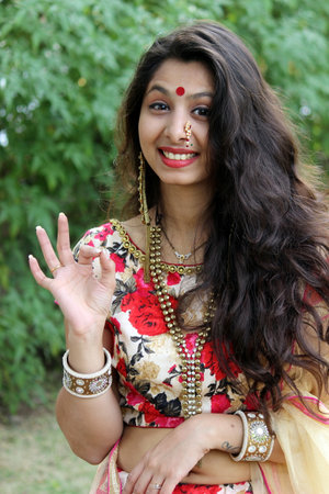 Indian woman with Marathi nose ring dressed up in traditional indian outfit. Saying wow, awesome, looking good, perfect etcの写真素材