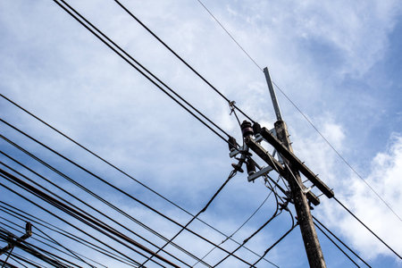 Electricity post with a lot of wires under blue sky and cloudsの写真素材