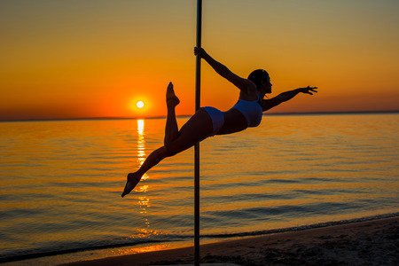 Athletic girl stands next to a portable pylon on the beach. Sand, sunset, beach.の写真素材