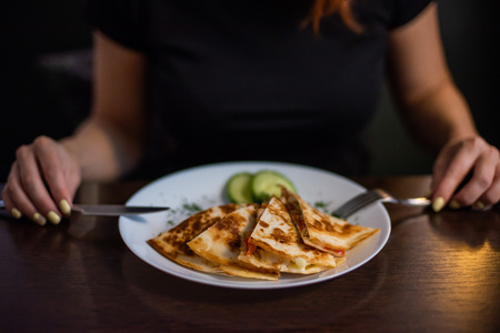 Woman eating delicious quesadilla in restaurant. Young redheaded woman is eating Mexican food in a cafeの写真素材
