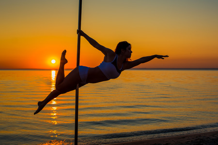 Athletic girl stands next to a portable pylon on the beach. Sand, sunset, beach.の写真素材