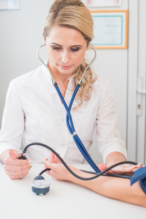 Doctor measuring pressure of the pregnant woman. Doctor taking blood pressure of female patient at officeの写真素材