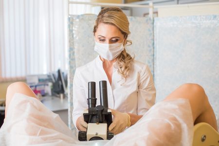 Professional gynecologist examining her female patient on a gynecological chairの写真素材