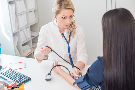 Doctor measuring pressure of the pregnant woman. Doctor taking blood pressure of female patient at officeの写真素材
