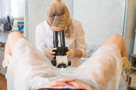 Professional gynecologist examining her female patient on a gynecological chairの写真素材