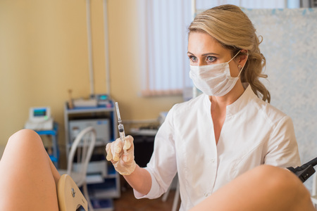 Gynecologist makes an injection. Attractive doctor gynecologist treats the patient.の写真素材