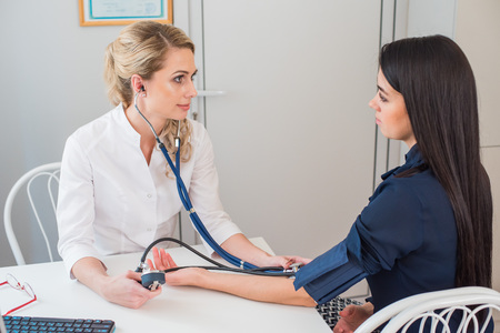 Doctor measuring pressure of the pregnant woman. Doctor taking blood pressure of female patient at officeの写真素材