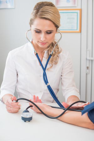 Doctor measuring pressure of the pregnant woman. Doctor taking blood pressure of female patient at officeの写真素材