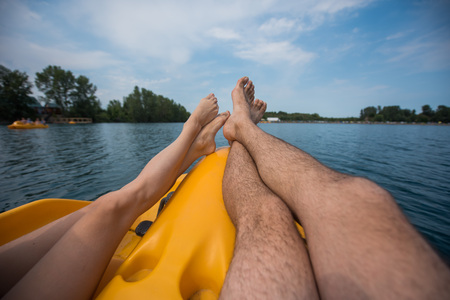 A couple of resting on a pedal boat on the lake. legs of men and women standing on the pedals of the boatの写真素材