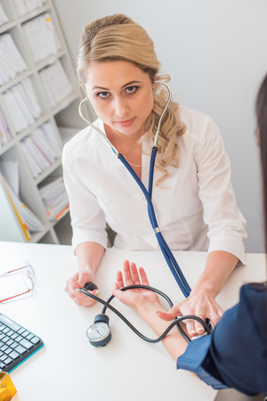 Doctor measuring pressure of the pregnant woman. Doctor taking blood pressure of female patient at officeの写真素材