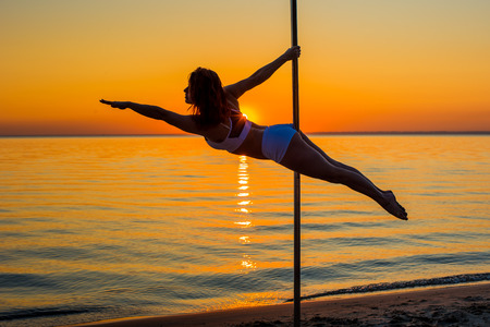 Athletic girl stands next to a portable pylon on the beach. Sand, sunset, beach.の写真素材