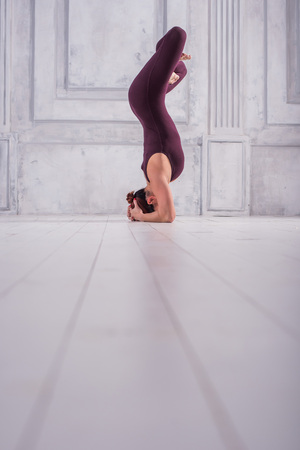 Woman meditating in a gym. Sporty young woman doing yoga practice on light background.の写真素材