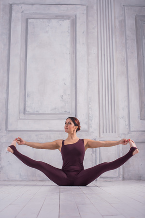 Woman meditating in a gym. Sporty young woman doing yoga practice on light background.の写真素材