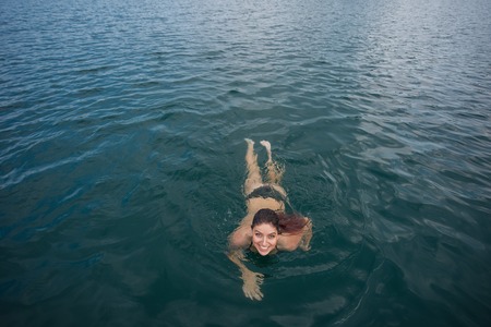 Young woman lies in the water on her back. Beautiful woman in a green bikini swimming in the lakeの写真素材