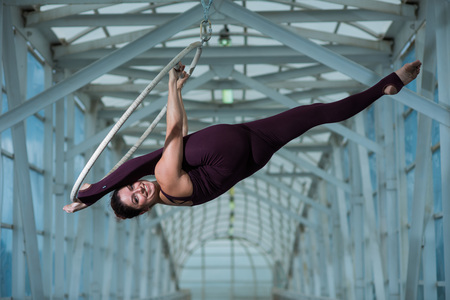 An air gymnast makes a Russian splits on an air hoop suspended on a metal truss. circus actress on the airy ring.の写真素材
