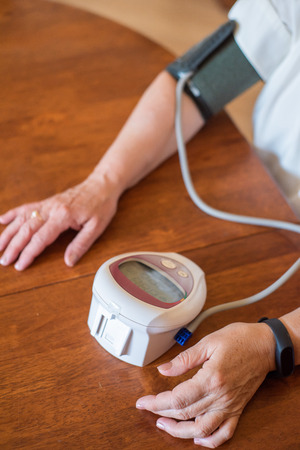 An elderly woman measures blood pressure with an electrical device. A pensioner uses a tonometer. Hands of an old woman.の写真素材