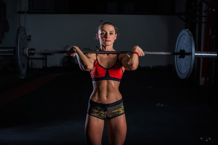 European muscular young fitness woman in khaki shorts doing heavy deadlift exercise in crossfit gym