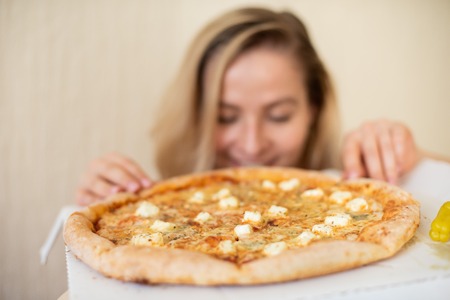 Portrait of a woman eating pizza. Beautiful young woman in black underwear eating pizza.の写真素材