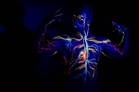 UV patterns body art of the circulatory system on a man's body. On the chest of a muscular athlete, veins and arteries are drawn with fluorescent dyes. The bodybuilder straightened the biceps.の写真素材