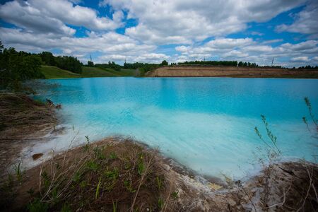 Alkaline solution. Ash dump dumping waste into the water. Ecological catastrophy. Turquoise dead water is like an oasis. The result of the waste plant in an artificial reservoirの写真素材