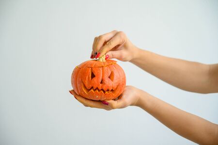 Female hands holding a pumpkin for Halloween. Close-up of a woman opens the jack-o'-lantern cover on a white background on the eve of all the saints. front viewの写真素材