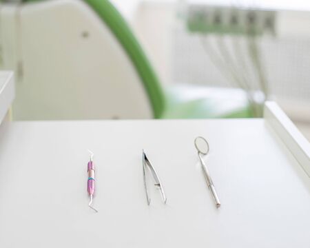 Sterile instruments lie on a table in the dentist office. A mirror, tweezers and a probe are on the...