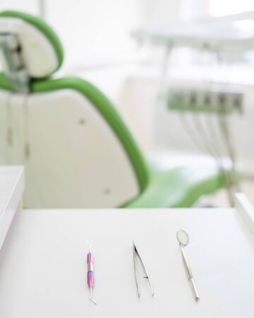 Sterile instruments lie on a table in the dentist office. A mirror, tweezers and a probe are on the doctor table. Oral hygiene, caries prevention, examination.の写真素材
