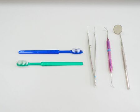 Dentists table with sterile tools on a white background top view. A mirror, tweezers, a probe and a...