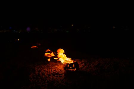 Tongues of flame in a pumpkin. jack-o-lantern on fire on a black background. Halloween symbol on the ground. Trick or treat. Close up.の写真素材
