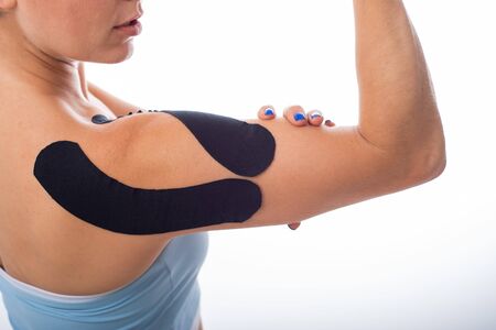 Female shoulder with kineziotape on a white background. Alternative medicine for sports injuries of...