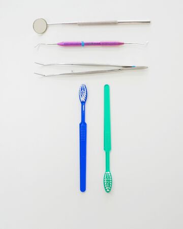 Dentists table with sterile tools on a white background top view. A mirror, tweezers, a probe and a toothbrush are on the doctor table. Oral hygiene, caries prevention, examination.の写真素材