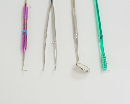 Dentists table with sterile tools on a white background top view. A mirror, tweezers, a probe and a toothbrush are on the doctor table. Oral hygiene, caries prevention, examination.の写真素材