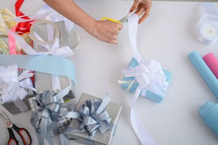 Close-up of female hands wrapping gifts for the new year. Woman holds handmade christmas gift....