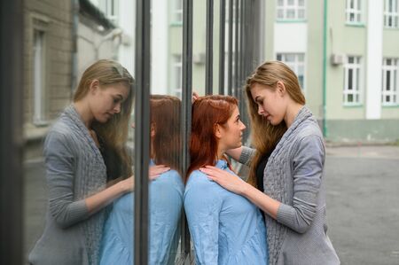 Portrait of two lesbians standing on the street and gently touching each other. LGBT Young loving...