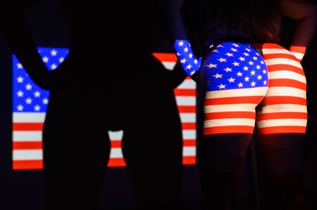 The projection of the flag of the United States of America on a beautiful large female ass. The projector shines with a flag on a female body.の写真素材