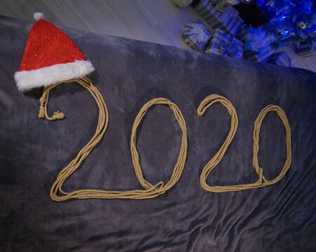 Happy New Year 2020. The inscription from the rope on the bed. Santa Claus hat.