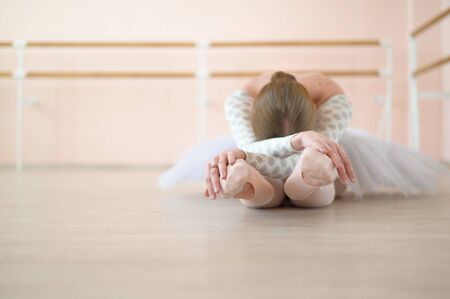 Beautiful ballerina in body and white tutu is training in a dance class. Young flexible dancer...