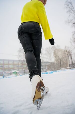 Figure skating on the street at an outdoor ice rink. Close-up of the skater's legs on ice. A woman goes in for sportsの写真素材