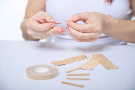 Female hands close-up sticks a patch on their face against aging. tape for a facelift....