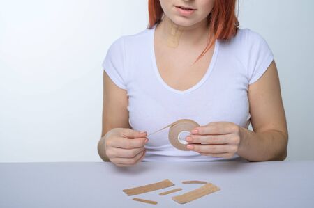 The faceless woman glues kinezio tape. Female hands close-up cut beauty applications for the face. An alternative to  hyaluronic acid.の写真素材