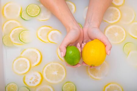 ripe lime in the hands of a woman. Top view Girl takes a milk bath with lemons. Citrus spa