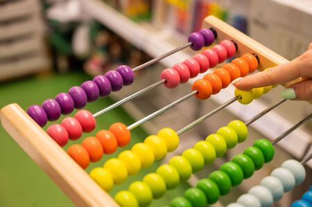 Closeup female hand calculating with balls on wooden rainbow abacus for number calculation. The concept of learning arithmetic for preschoolersの写真素材