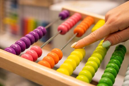 Closeup female hand calculating with balls on wooden rainbow abacus for number calculation. The concept of learning arithmetic for preschoolers.の写真素材