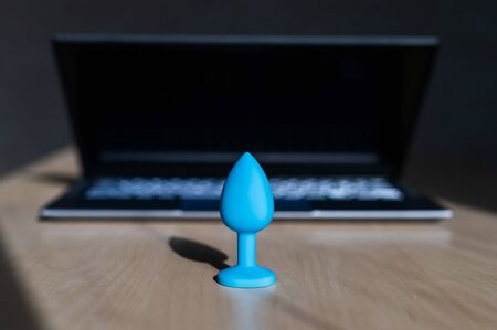 Blue latex anal plug the laptop on the table. The concept of virtual sex on the Internet. Anus extender toy for adults.の写真素材