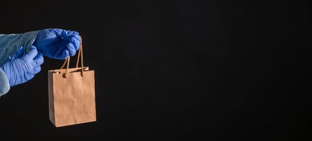 Express home delivery in the epidemic of coronavirus. Courier in gloves with a paper bag. Packaging...