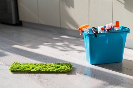 A blue bucket of cleaning products in the kitchen. A set of detergents and a rag for home cleaning on the floor in the apartment. No people.の写真素材